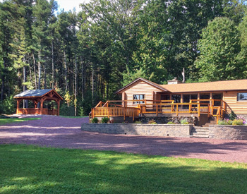  12 x 16 Rough Cut Cedar Gable Ramada shown with no deck, open gable, weathered wood asphalt shingles, 8- 6" tall posts, cedar stain/sealer, and rough cut gazebo style rails.